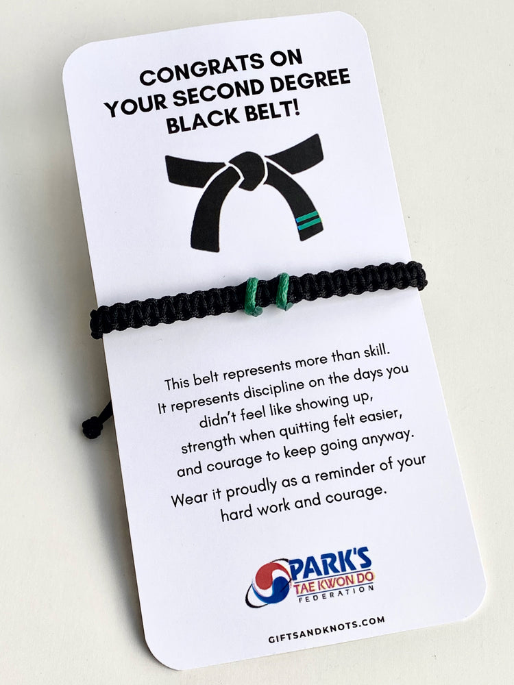 Black belt bracelet with a congratulatory card on a white background