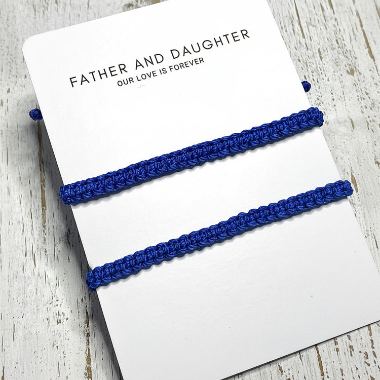 Two blue braided bracelets on a card with 'Father and Daughter Our Love is Forever'.