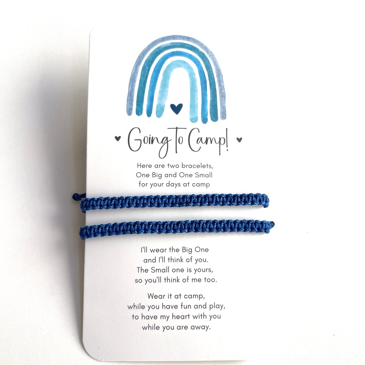 Two blue bracelets on a card with a rainbow design and text about going to camp.