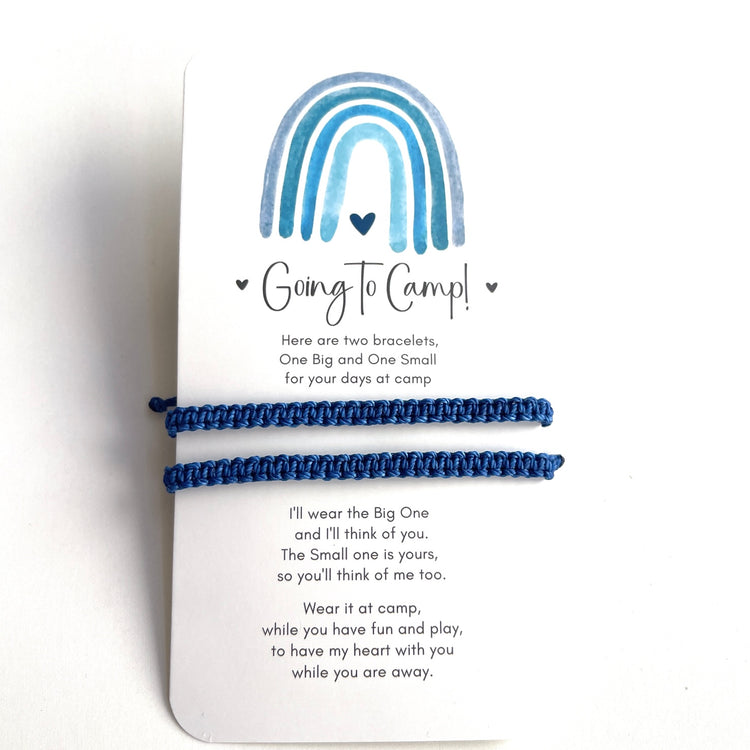 Two blue bracelets on a card with a rainbow design and text about going to camp.
