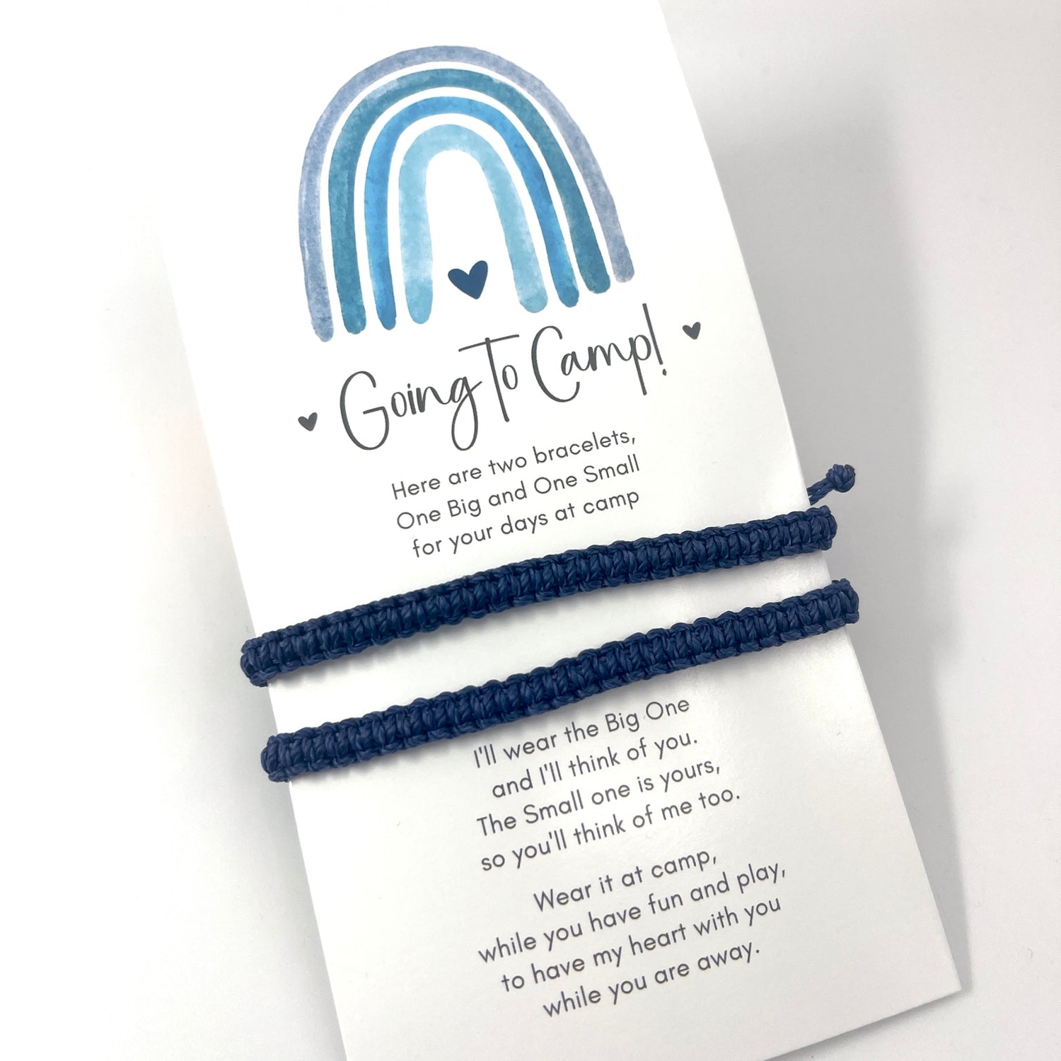 Two navy blue bracelets on a card with a rainbow design and text.