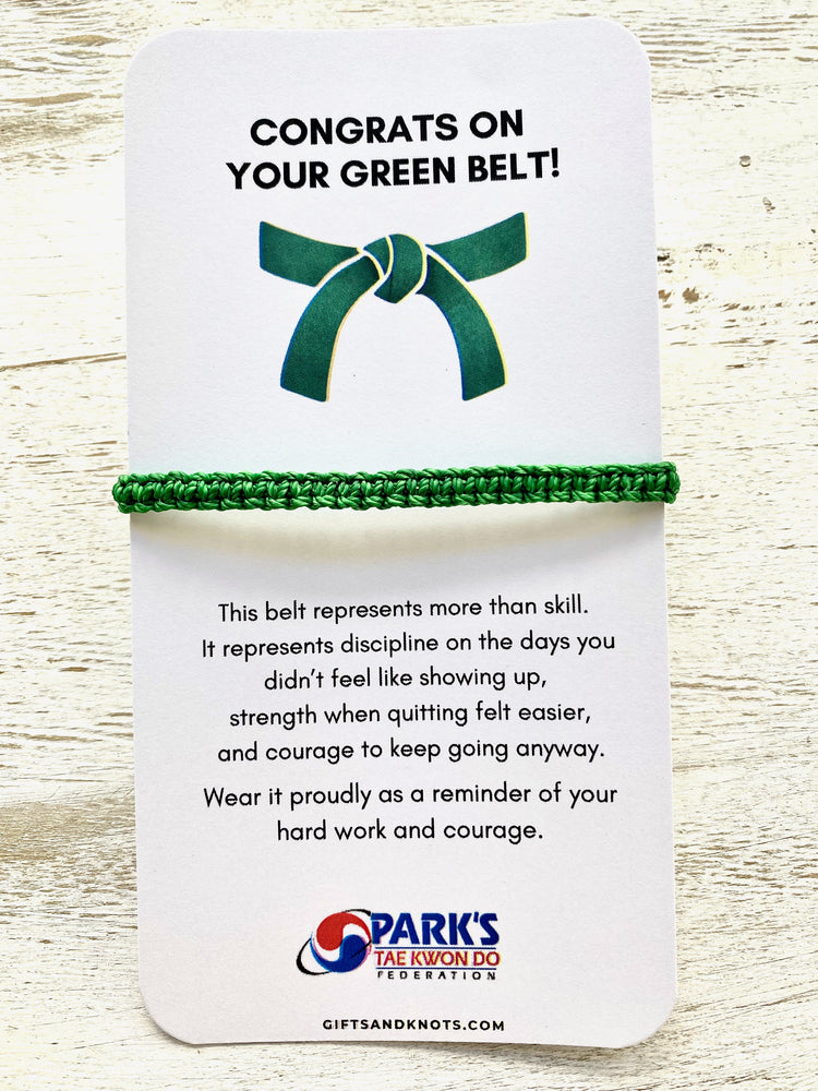 Green belt with a white card congratulating on a green belt, featuring text and Park's Tae Kwon Do Federation logo.