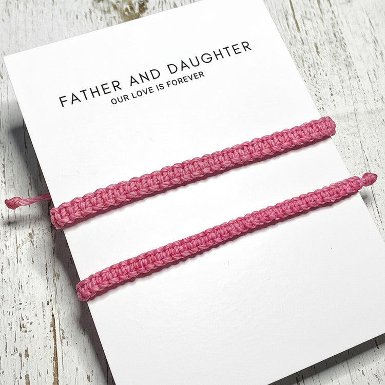 Two pink braided bracelets on a card with 'Father and Daughter Our Love is Forever' .