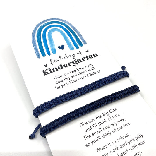 Two Navy Blue Matching bracelets with a card that says First day of Kindergarten with a blue shades rainbow and a heart. The card says &#39;Here are two bracelets, One Big and One Small for your First Day of School. I&#39;ll wear the Big One and I&#39;ll think of you. The small one is yours, so you&#39;ll think of me too. Wear it to school, you work and you play heart with you way.